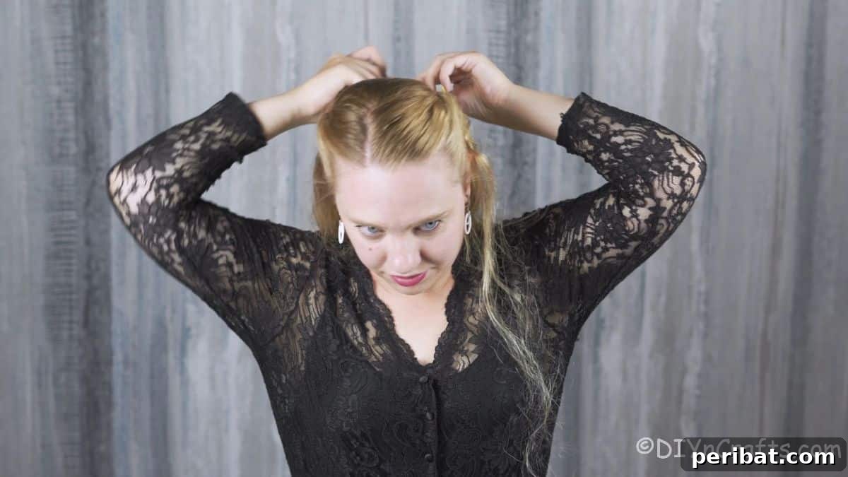 Two twisted sections of hair being brought together and carefully secured at the back of the head, ready for braiding.
