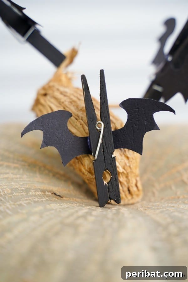 A completed Halloween bat clothespin perched on a decorative pumpkin, ready to clip or adorn.