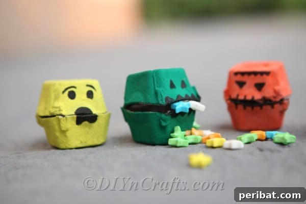 A collection of vibrant monster treat boxes, cleverly crafted from egg cartons and adorned with googly eyes, resting on the ground.