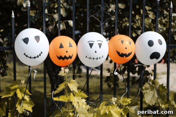 A row of creatively decorated Halloween balloons tied along a black fence line outdoors, adding a festive touch to the exterior decor.