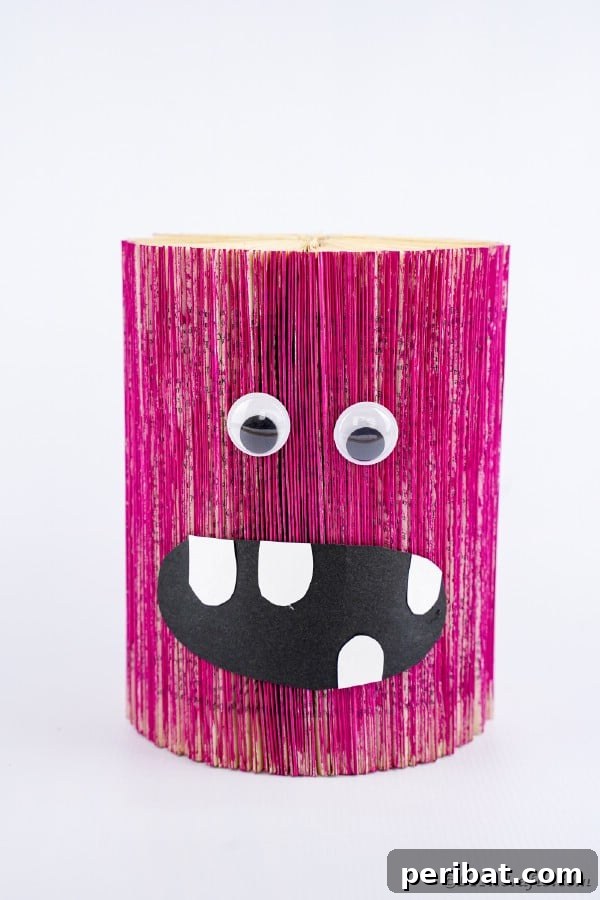 A whimsical pink monster crafted from an old book, sitting on a white table, showcasing creative upcycling for Halloween.
