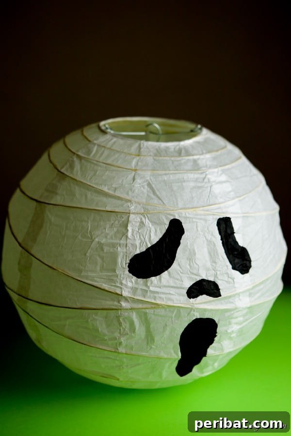 A charming ghost paper lantern casting a soft glow on a green table in a dimly lit room, creating a spooky ambiance.