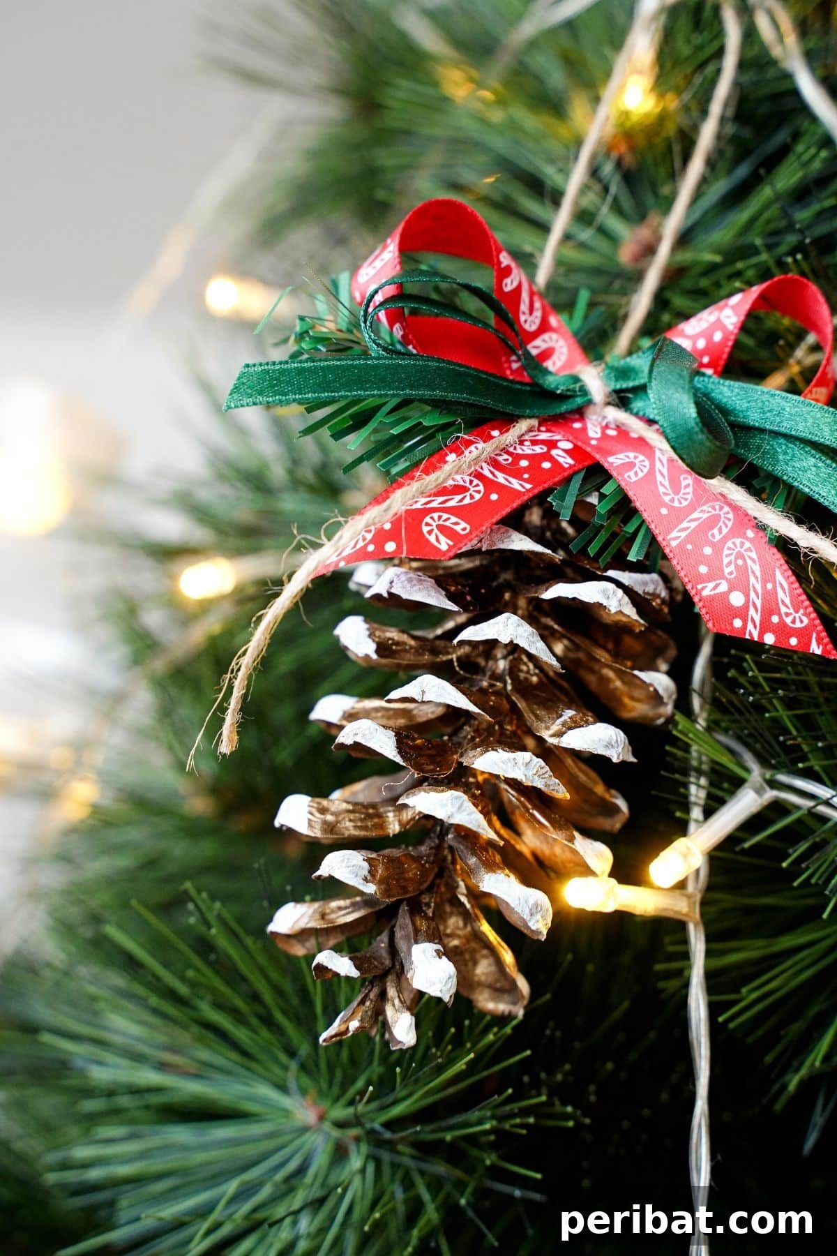 DIY Pinecone Christmas Ornaments 12 A beautifully decorated pinecone ornament hanging gracefully on a branch of a lit Christmas tree