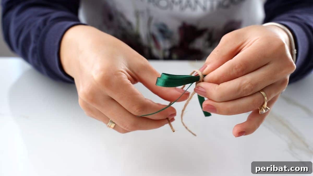 DIY Pinecone Christmas Ornaments 8 Hands tying a red ribbon into a bow, preparing it for attachment to a pinecone ornament