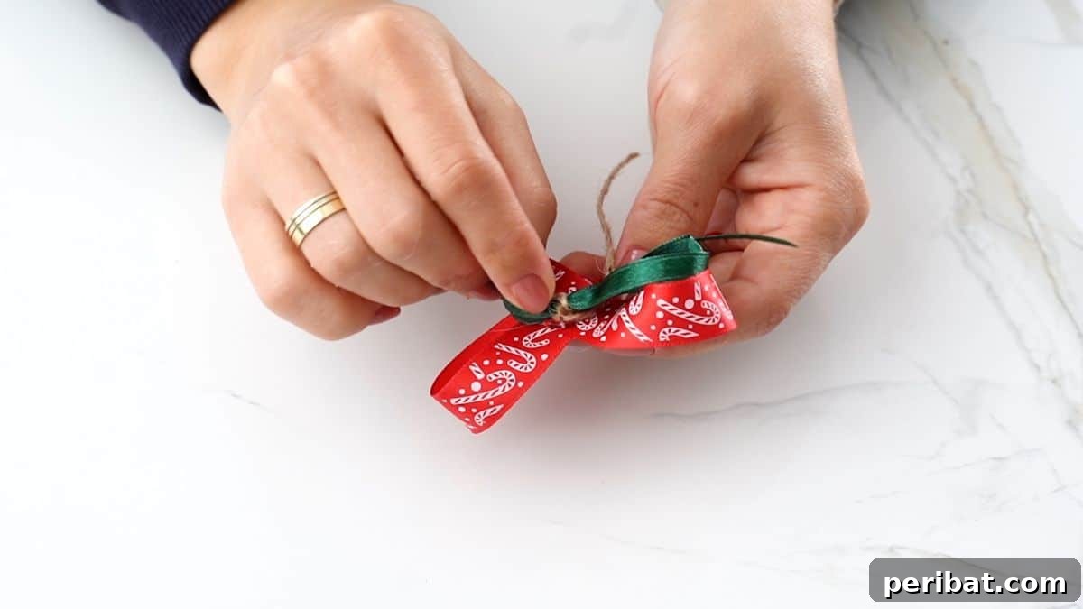 DIY Pinecone Christmas Ornaments 9 A person meticulously forming a small bow from a green Christmas ribbon, ready to be added to the ornament