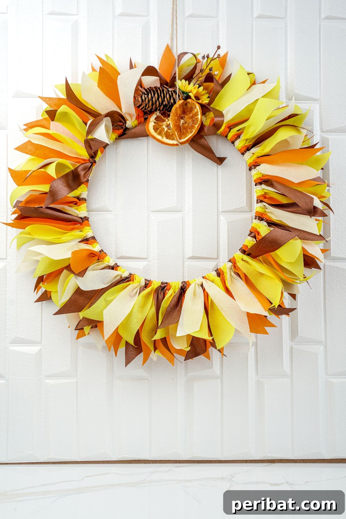 Autumn Farmhouse Wreath from Upcycled Fabric Scraps 2 A beautifully crafted rustic fall rag wreath hanging on a white wall, showcasing autumnal colors and textures.