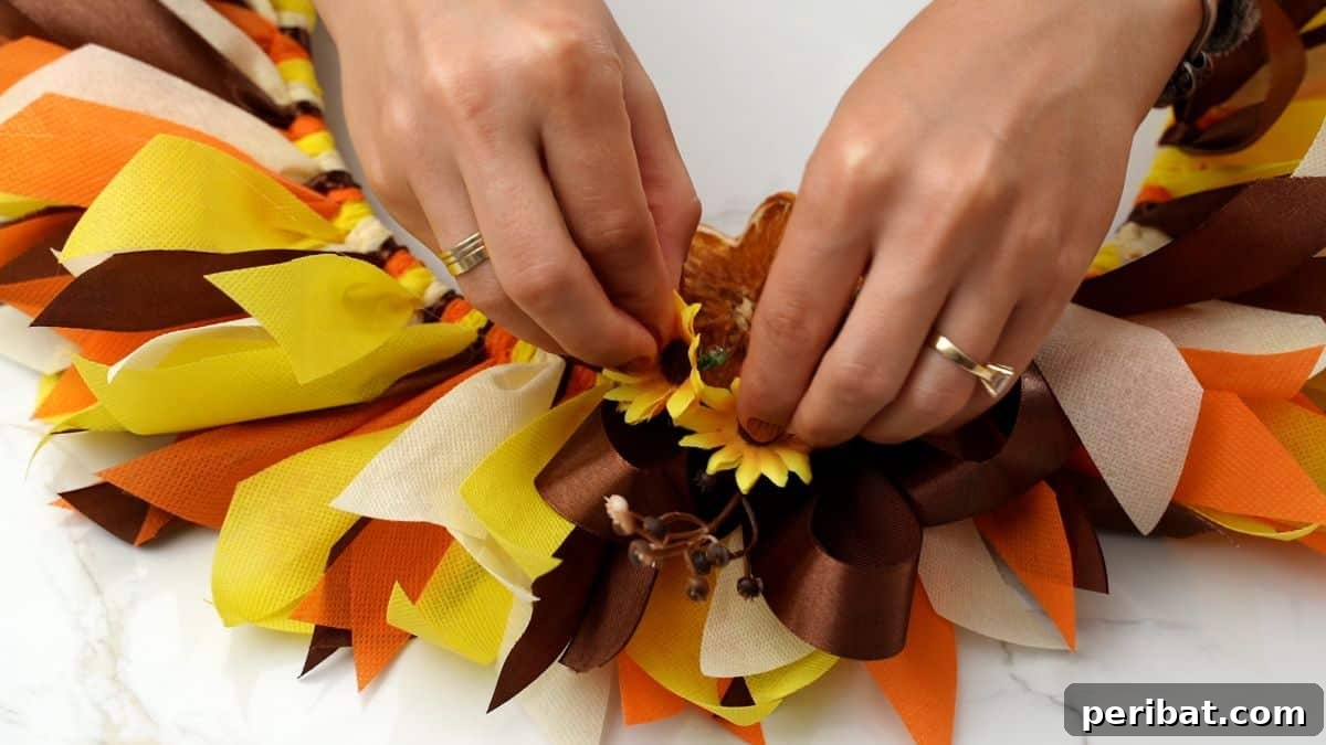 Autumn Farmhouse Wreath from Upcycled Fabric Scraps 14 Artificial flowers being precisely glued onto a fall rag wreath, enhancing its autumnal beauty.
