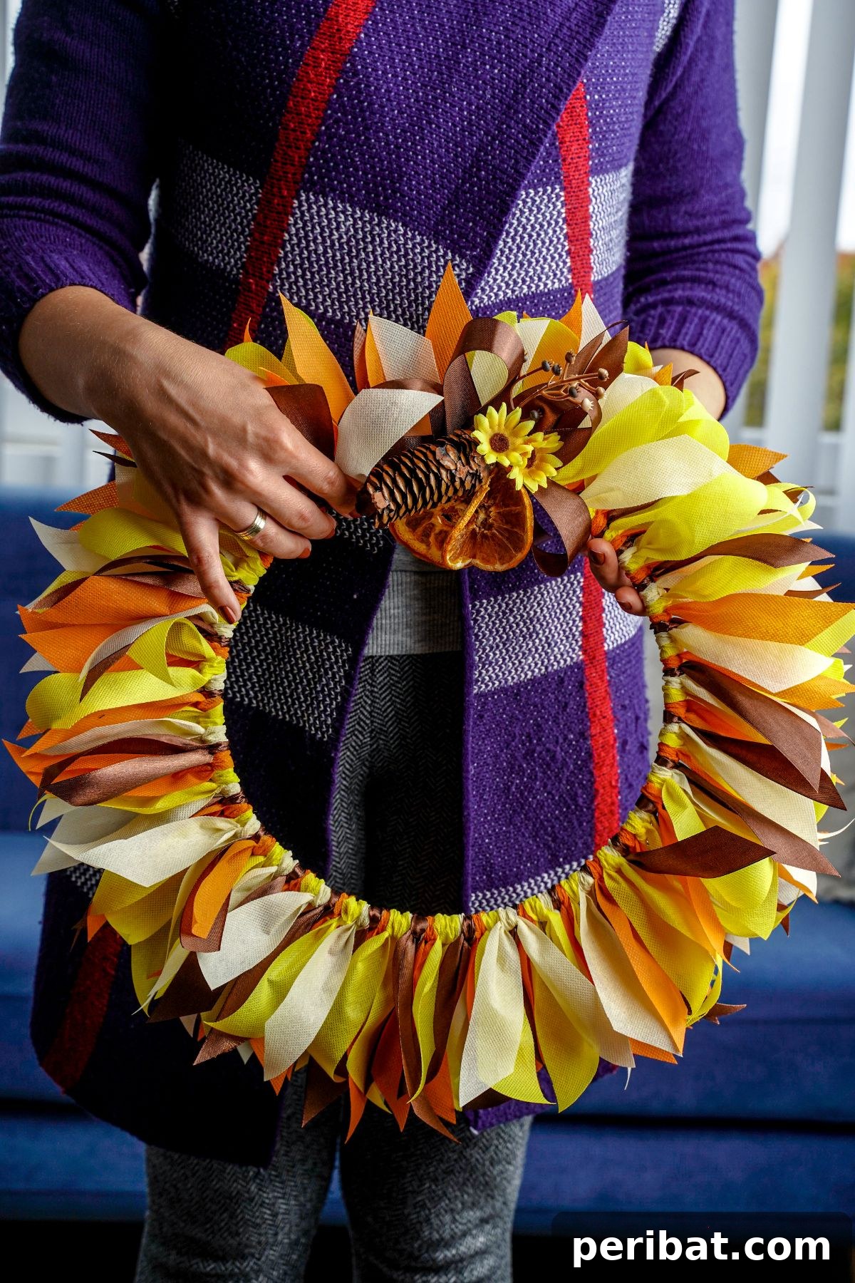 Autumn Farmhouse Wreath from Upcycled Fabric Scraps 15 A woman holding her freshly made rustic fall rag wreath, showcasing the finished craft.