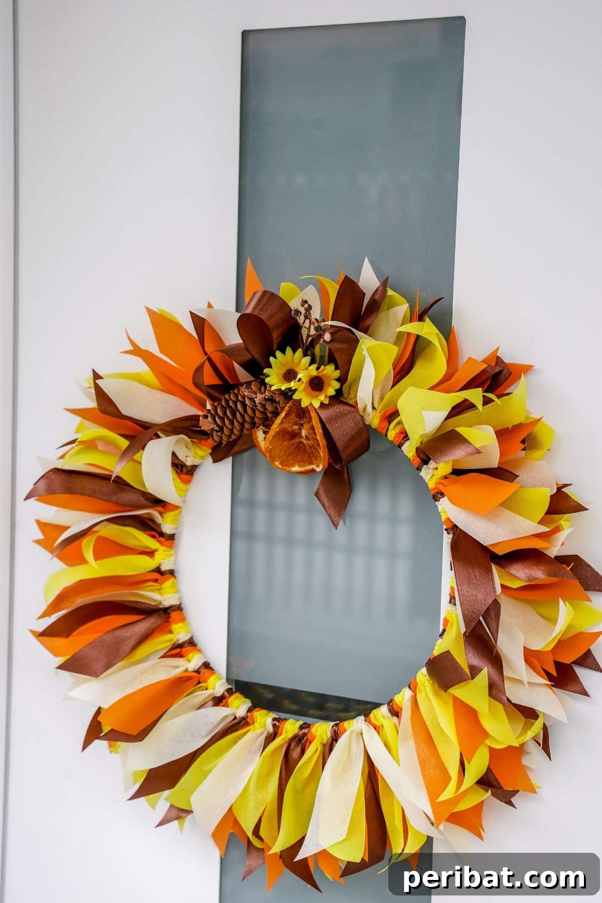 Autumn Farmhouse Wreath from Upcycled Fabric Scraps 18 A beautiful fall rag wreath hanging centrally on a white and glass front door, creating a welcoming autumn entrance.