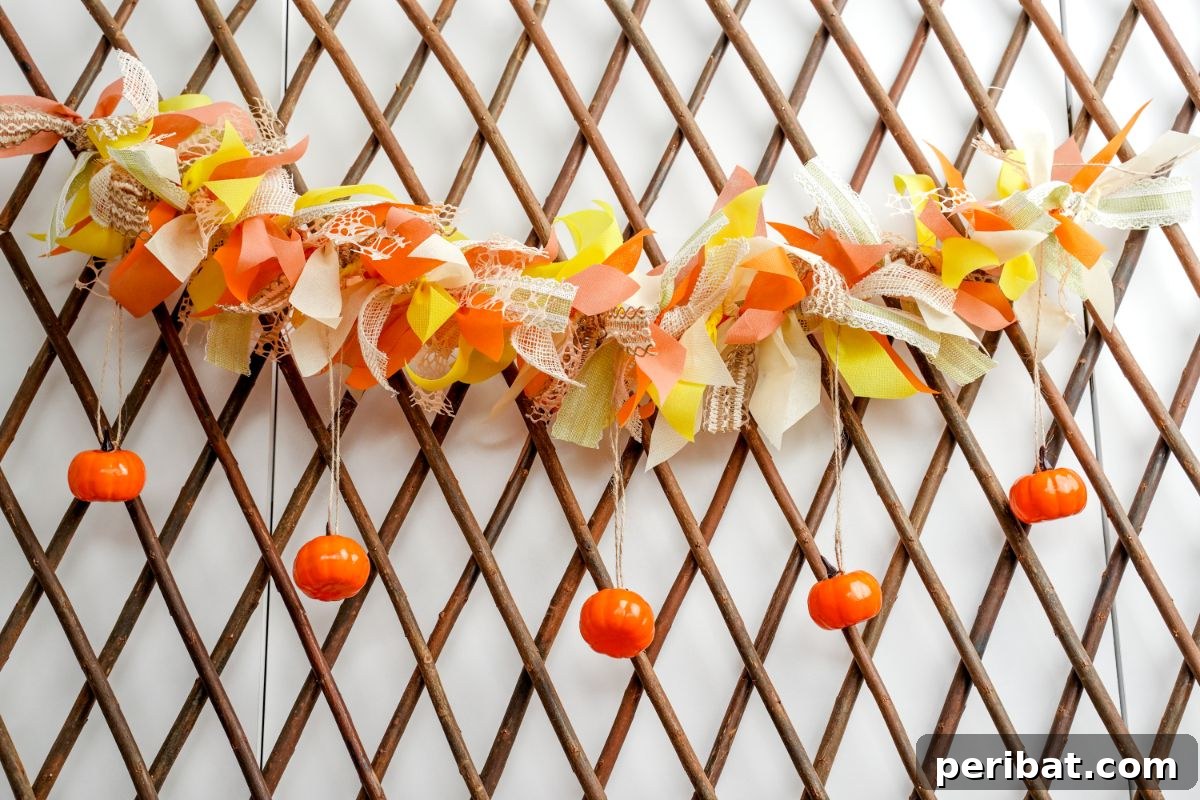 A finished mini pumpkin and ribbon garland hanging on a decorative wood lattice wall