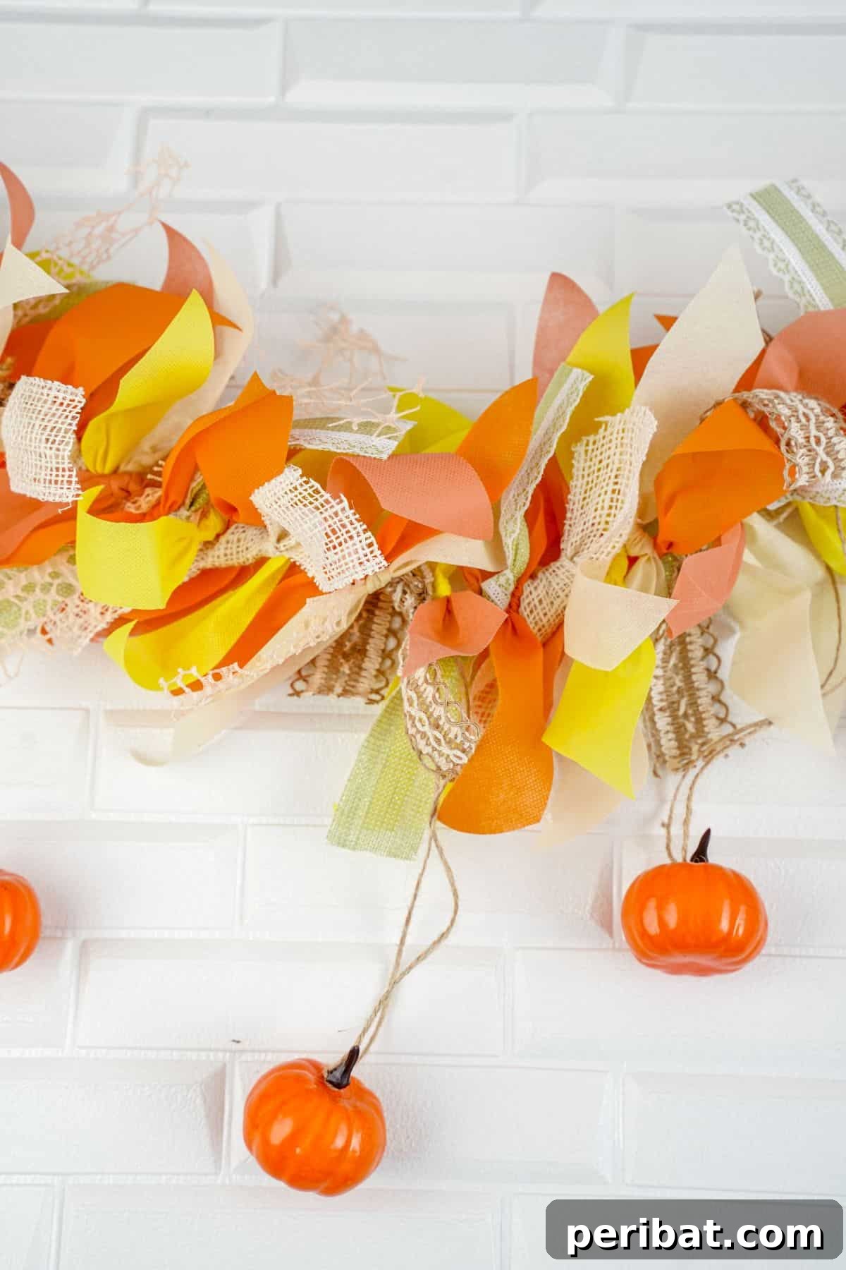 A close-up of a finished orange and yellow scrap fabric garland draped on a white counter