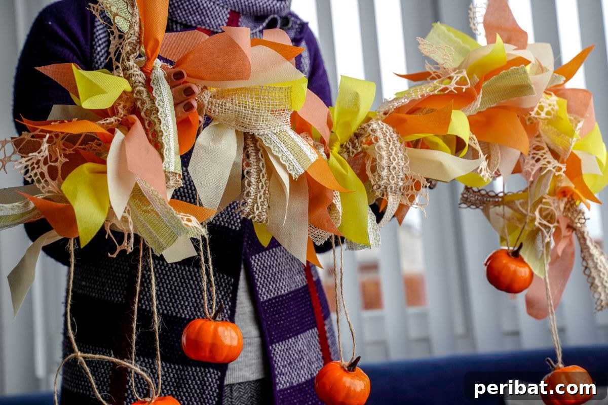 A woman holding a finished fall rag garland with pumpkins and colorful fabrics