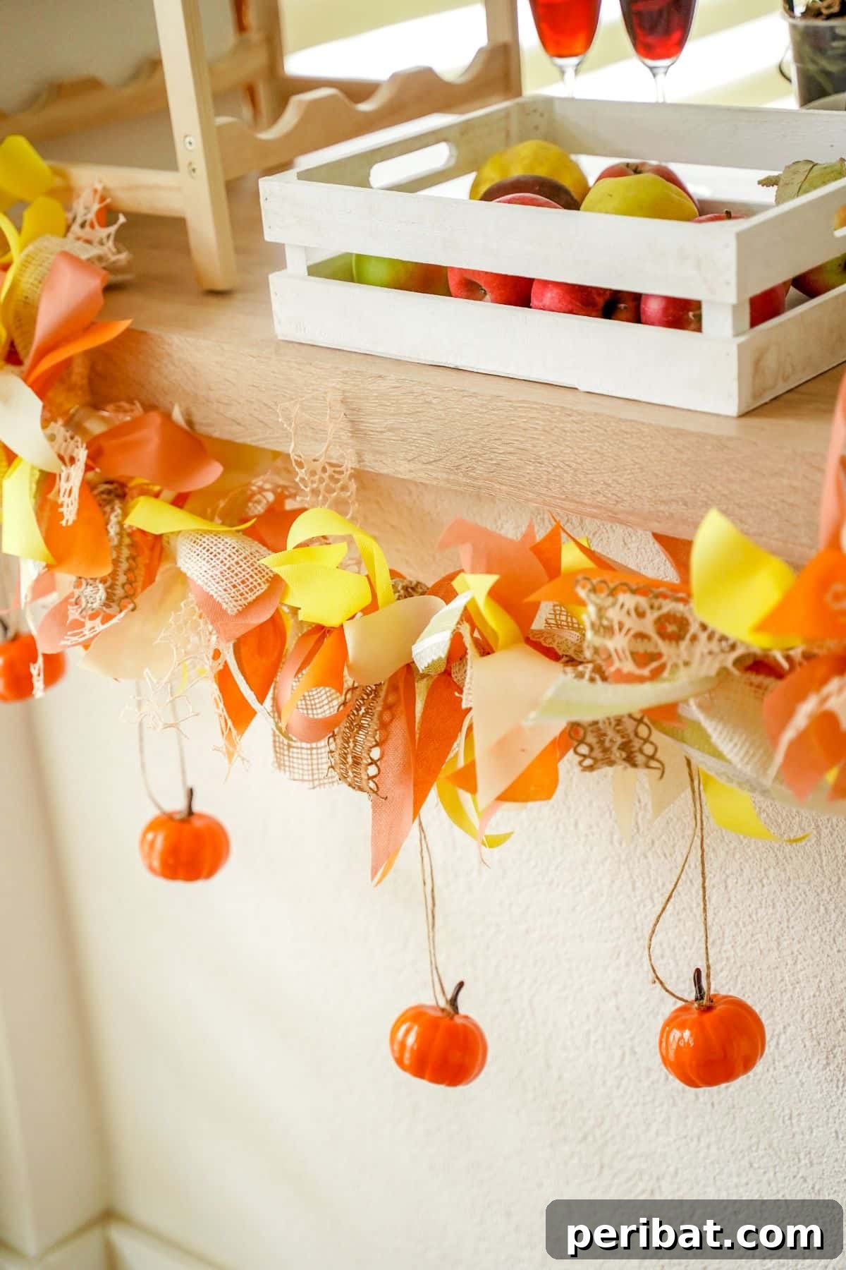 Close-up of mini pumpkins and fabric strips hanging down from a fall garland