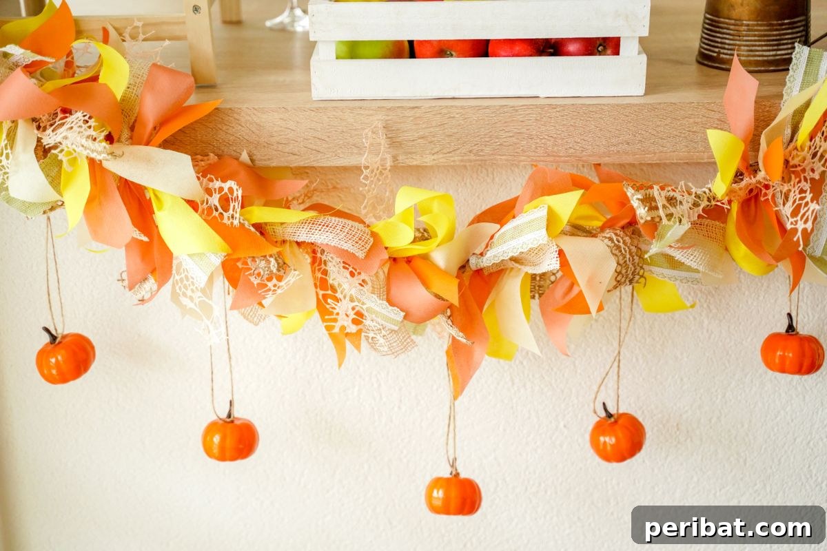 Close-up of a fall rag garland featuring fabric strips, ribbon, and mini pumpkins