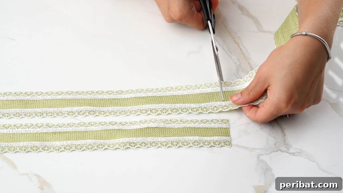 A hand cutting a strip of green lace ribbon with scissors