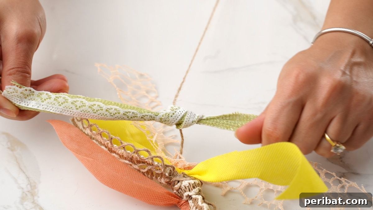 Close-up of hands tying a strip of burlap lace onto natural twine