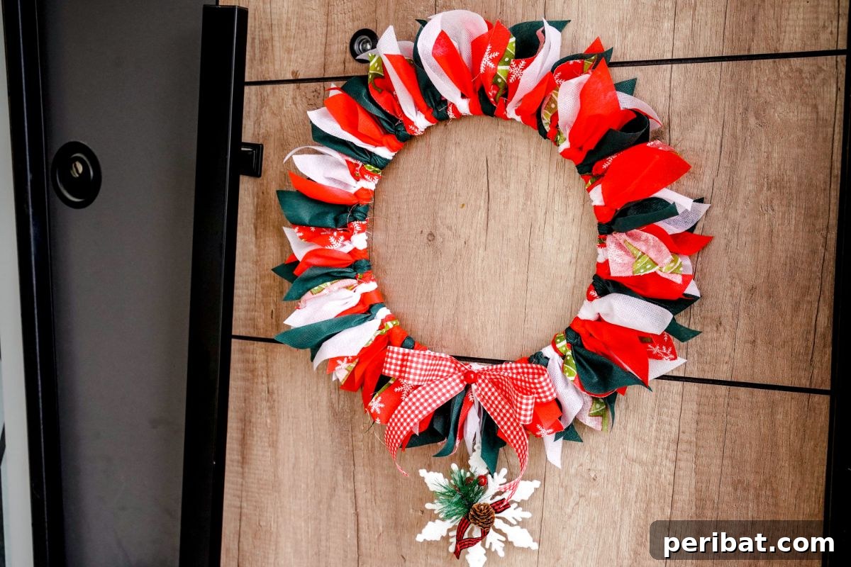 Effortless Festive Fabric Wreath 13 A festive red, green, and white Christmas rag wreath, beautifully crafted and hanging on a rustic wood-paneled wall, adding a cozy holiday touch.