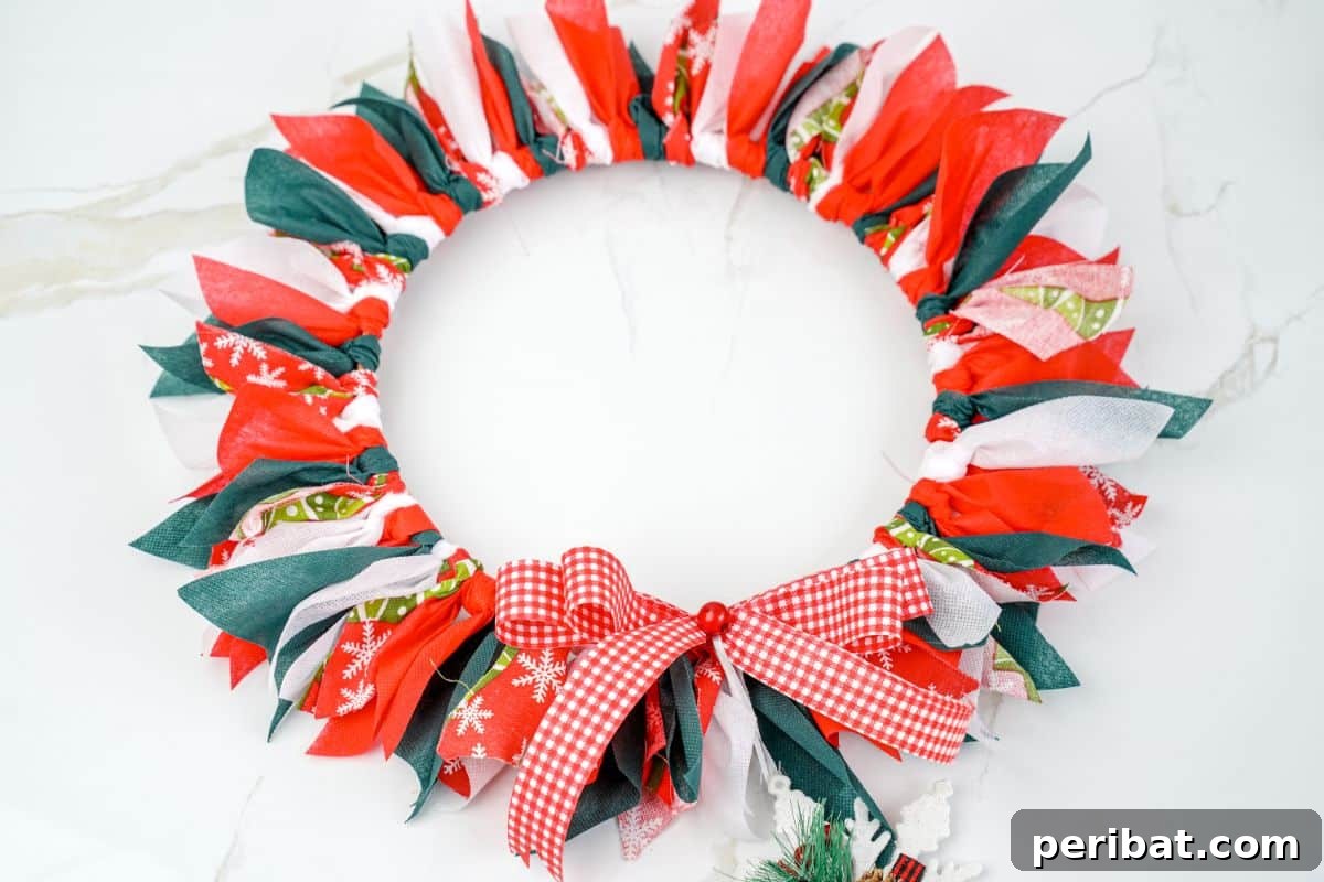 Effortless Festive Fabric Wreath 15 A festive and colorful Christmas rag wreath adorned with various ribbons and fabric patterns, artfully displayed on a polished marble table.