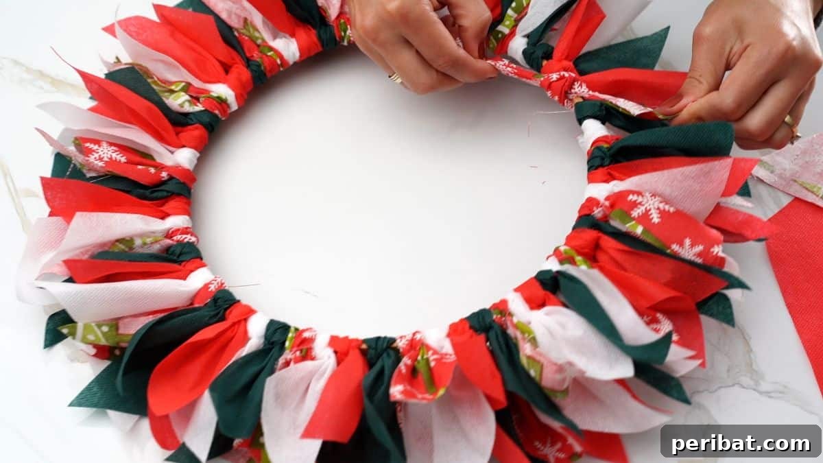 Effortless Festive Fabric Wreath 10 A close-up shot of hands tying colorful holiday ribbon on wreath form, showcasing the variety of festive fabrics and ribbons used.
