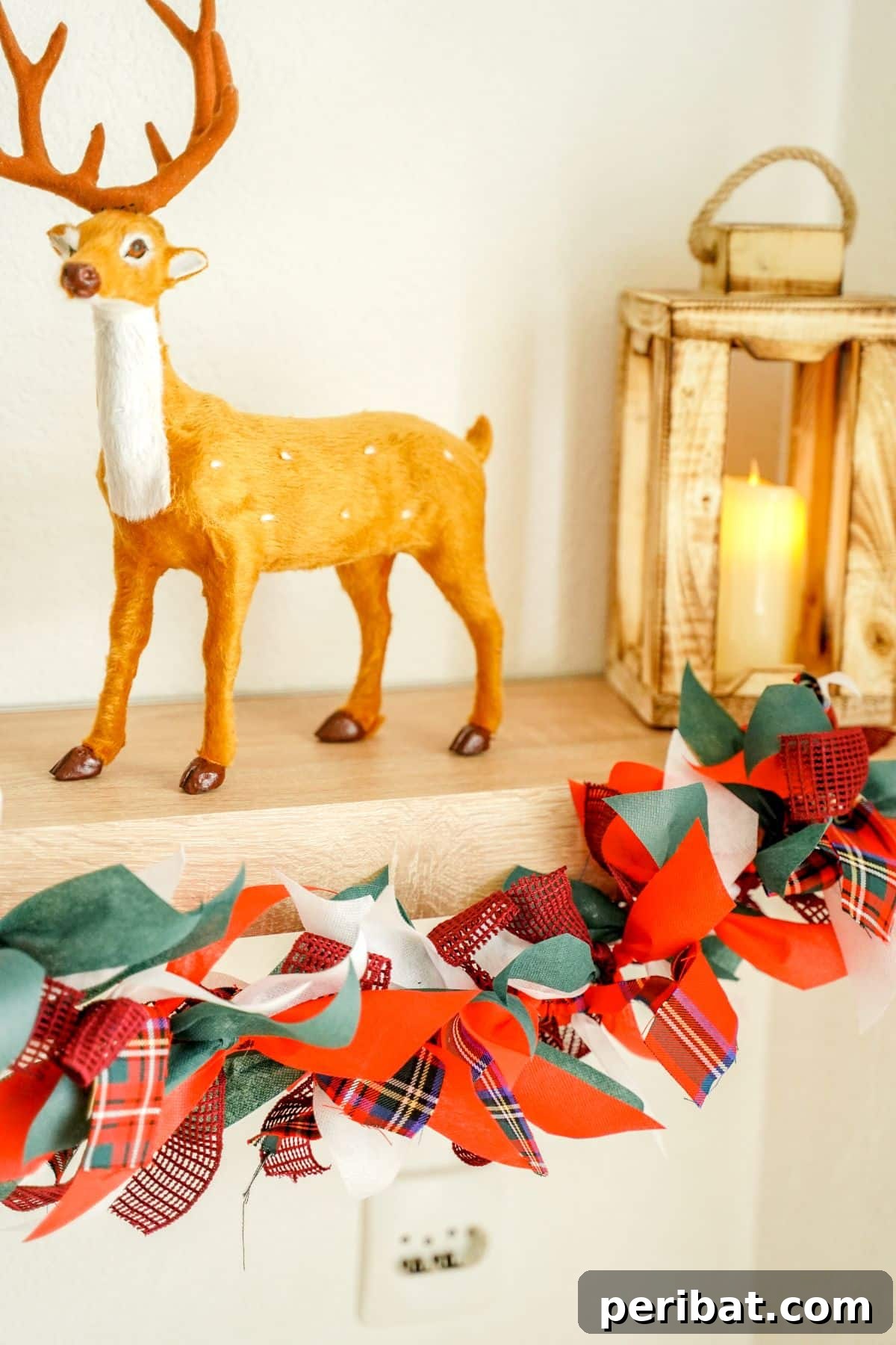 Handcrafted Rustic Christmas Rag Garland 2 red, green, and white fabric garland hanging on shelf by fake deer and lantern