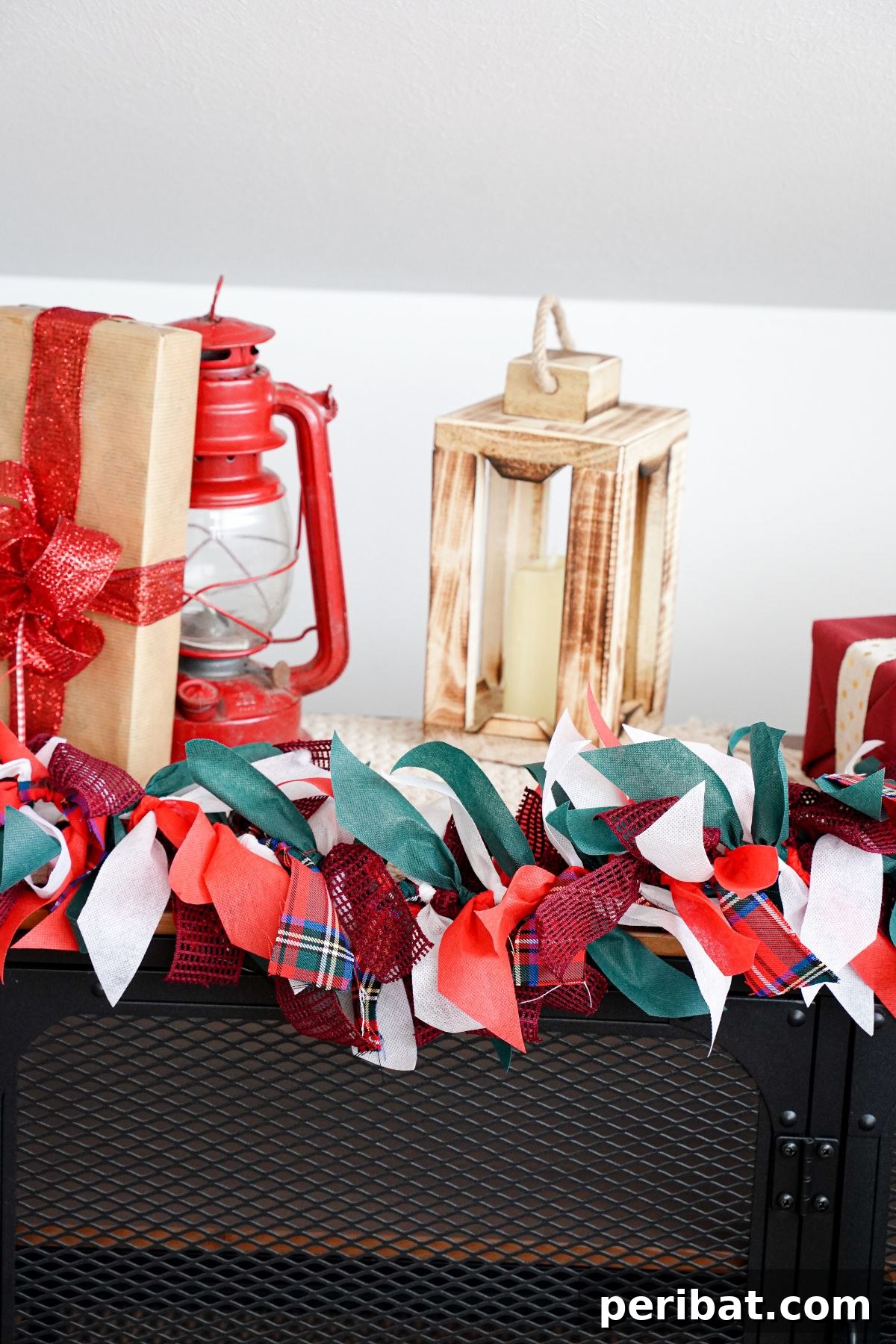 Handcrafted Rustic Christmas Rag Garland 14 colorful holiday garland on shelf in front of gift and lanterns