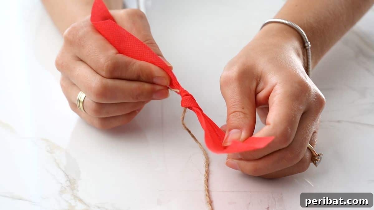 Handcrafted Rustic Christmas Rag Garland 8 red ribbon being tied on twine