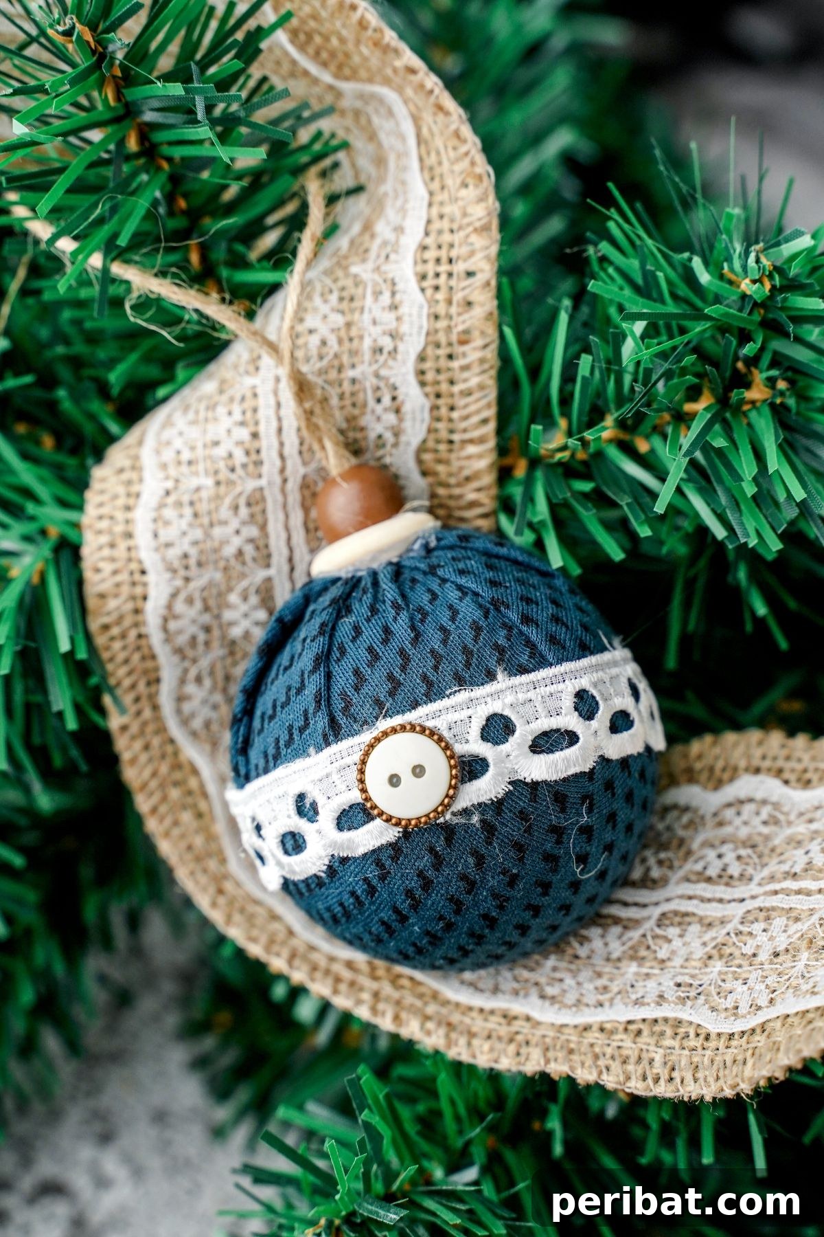 Chic Fabric Holiday Bauble 2 Elegant green and lace fabric ornament resting on lace burlap with Christmas tree in background