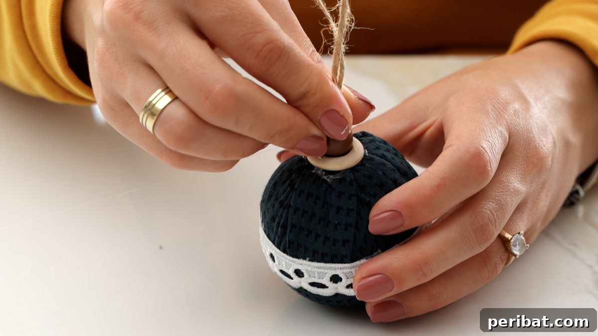 Chic Fabric Holiday Bauble 13 Gluing the wooden bead with twine loop onto the wooden ring at the top of the ornament