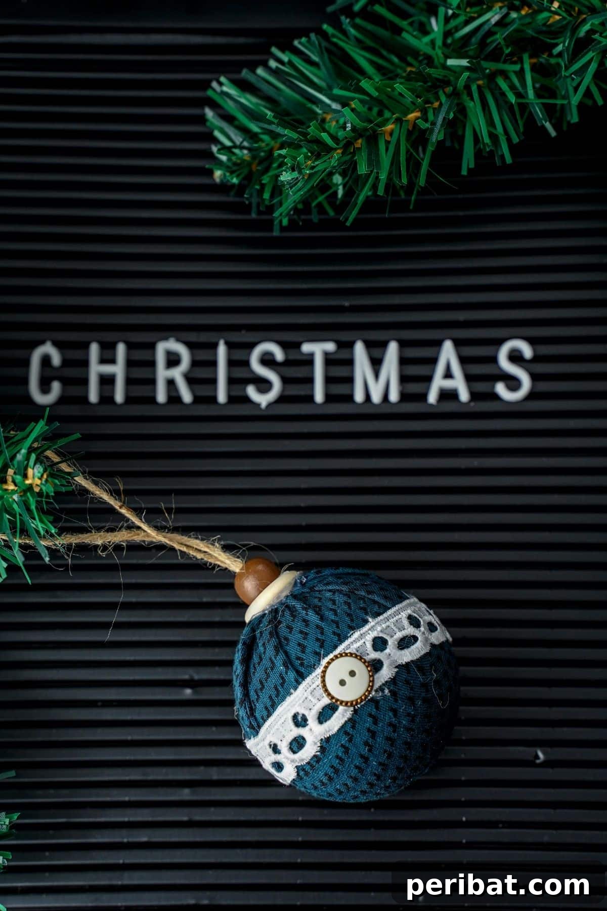 Chic Fabric Holiday Bauble 14 A fabric ball ornament hanging next to a black Christmas sign with artificial garland