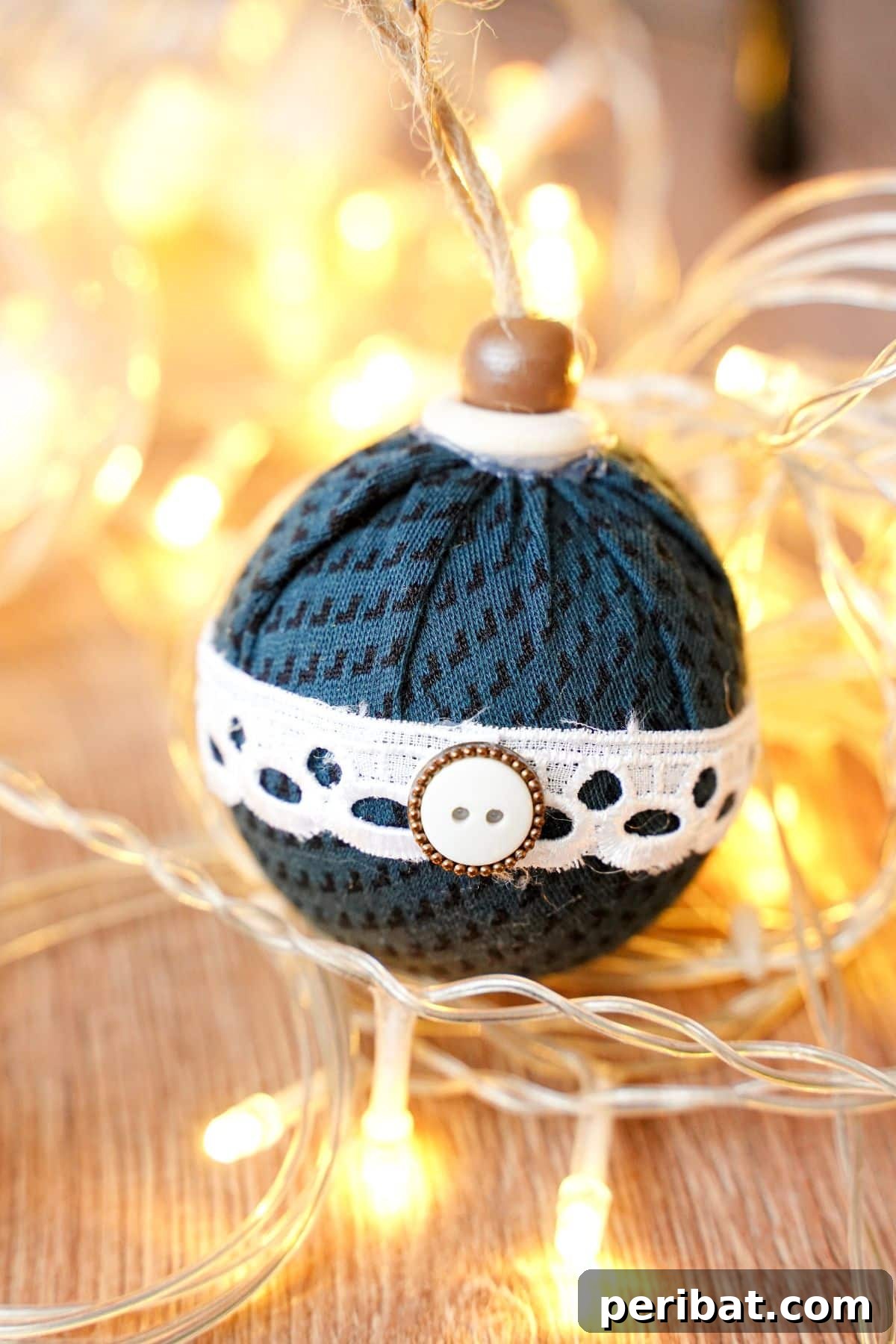 Chic Fabric Holiday Bauble 15 Close-up of a fabric ball ornament resting on a table, with soft fairy lights in the background