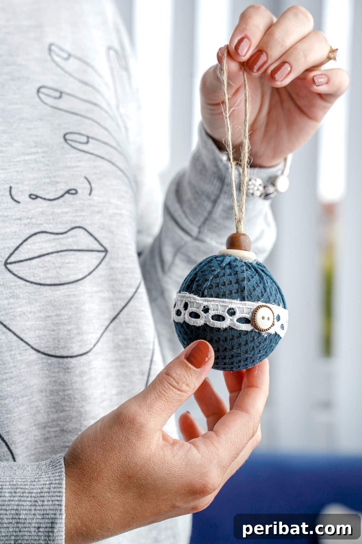 Chic Fabric Holiday Bauble 17 A woman's hands gently holding a completed fabric ball ornament, ready for display