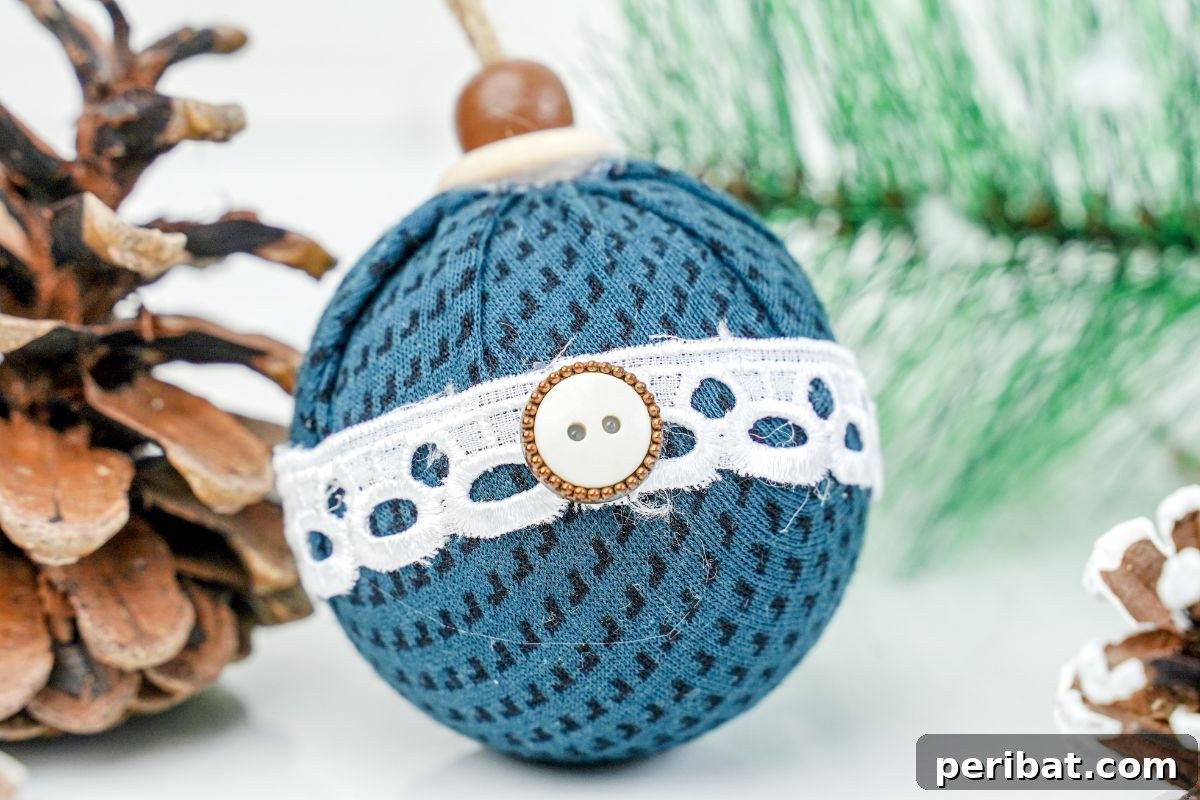 Chic Fabric Holiday Bauble 3 Close-up of a blue checkered fabric ball Christmas ornament next to a pinecone on a table