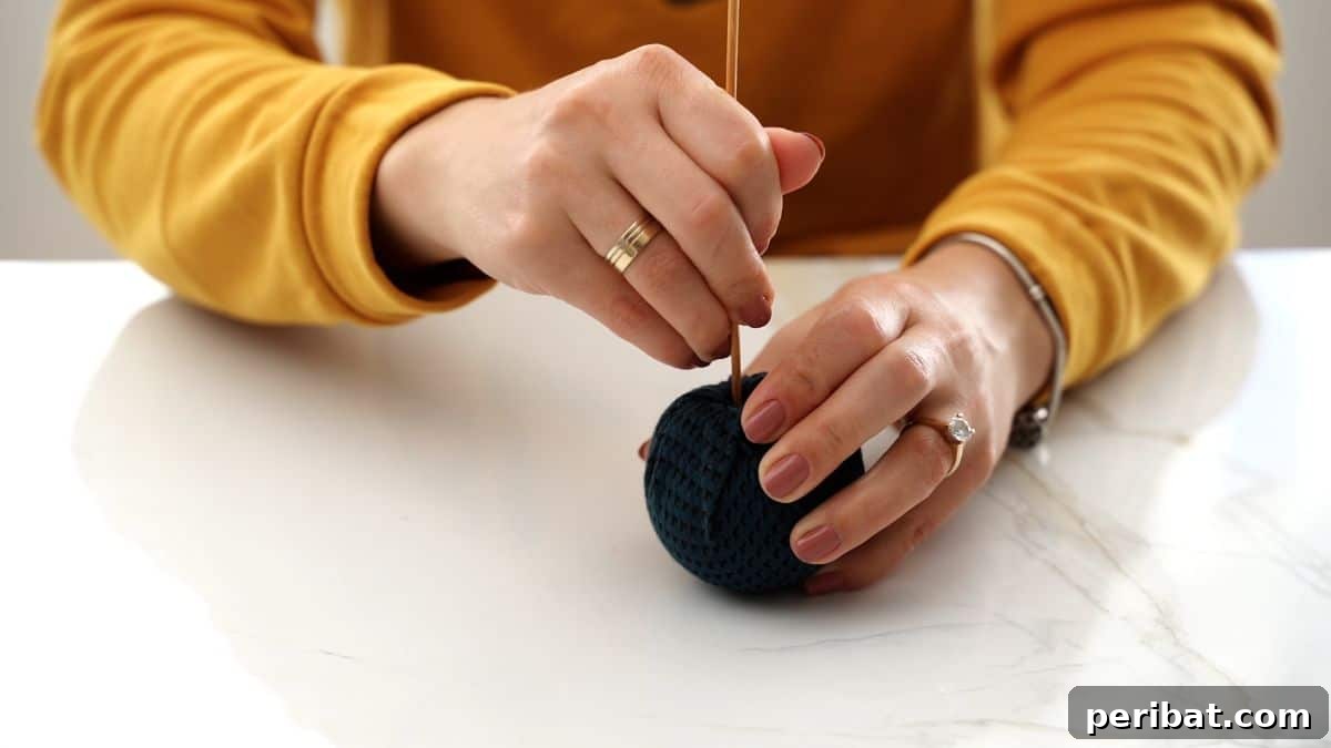 Chic Fabric Holiday Bauble 7 Tucking fabric securely into the ornament opening with a tool