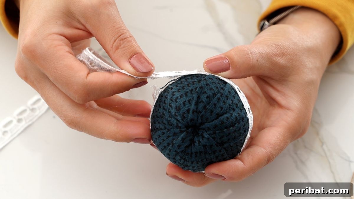 Chic Fabric Holiday Bauble 10 Gluing a strip of lace neatly around the middle of a fabric ball ornament