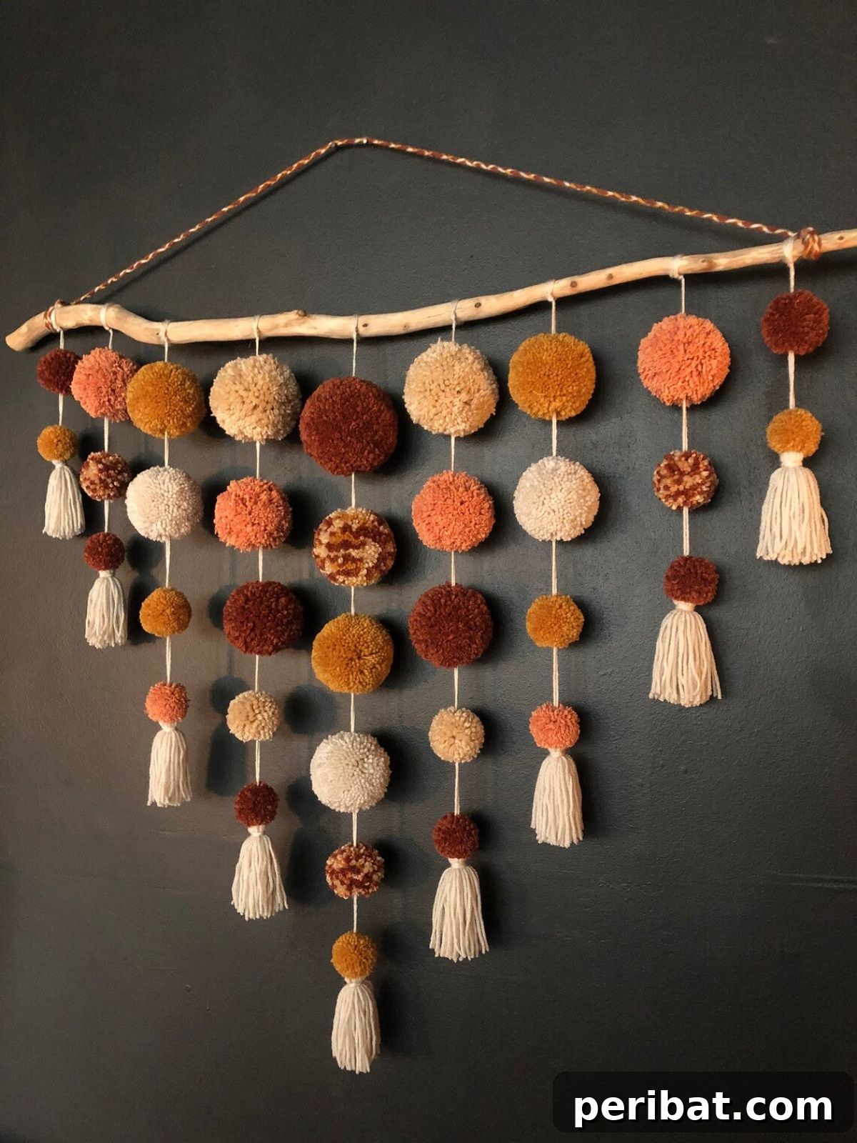 120 Inspiring DIY Boho Decor Ideas and Projects 64 Elevate bare walls with an extra-large rustic pom-pom wall hanging, featuring handmade fluffy poms and tassels on driftwood for '70s boho vibes.