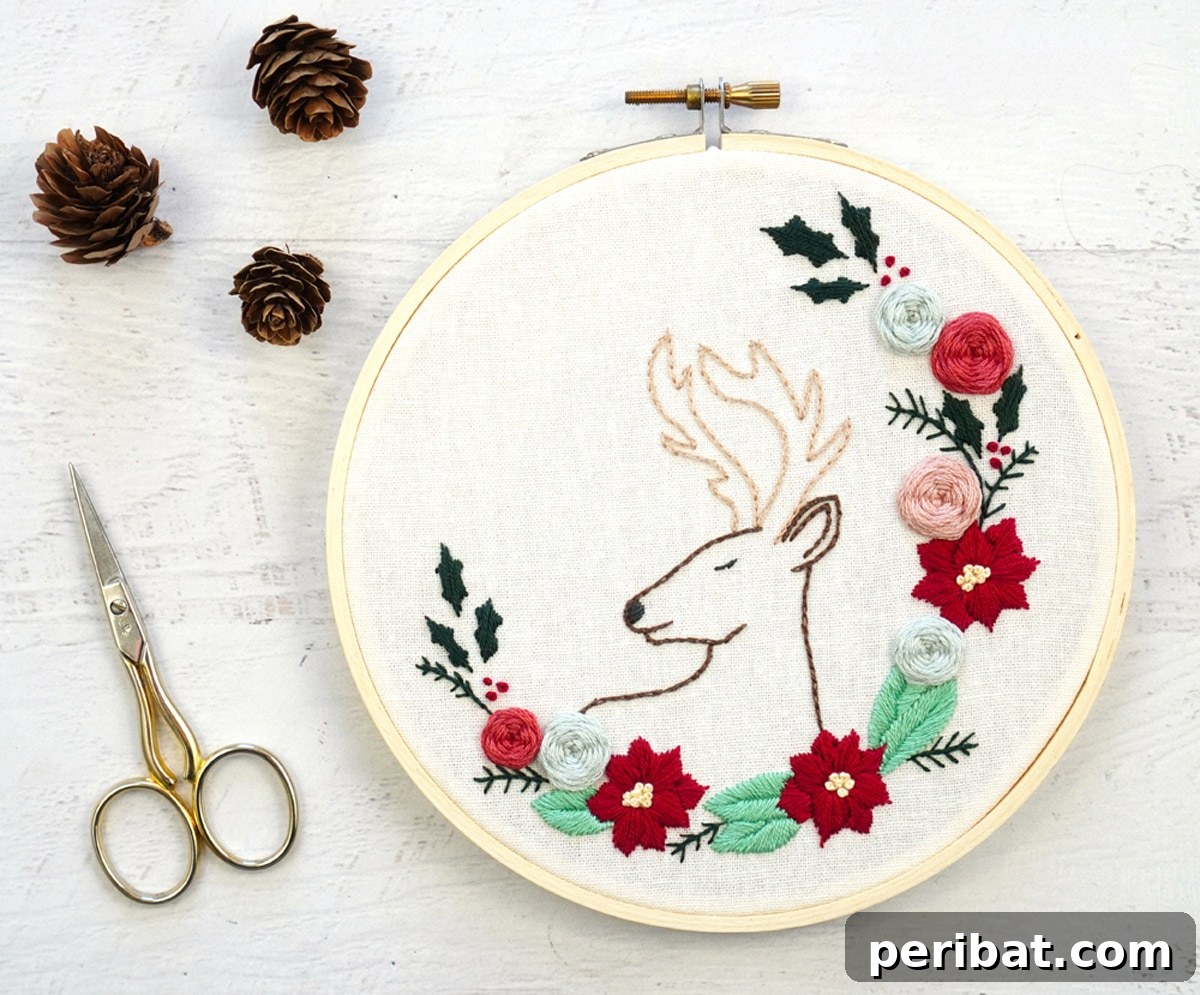 Stitch Your Way to a Merry Christmas: 48 DIY Embroidery Designs 13 A charming Christmas deer embroidery pattern adorned with a floral wreath, set next to scissors.
