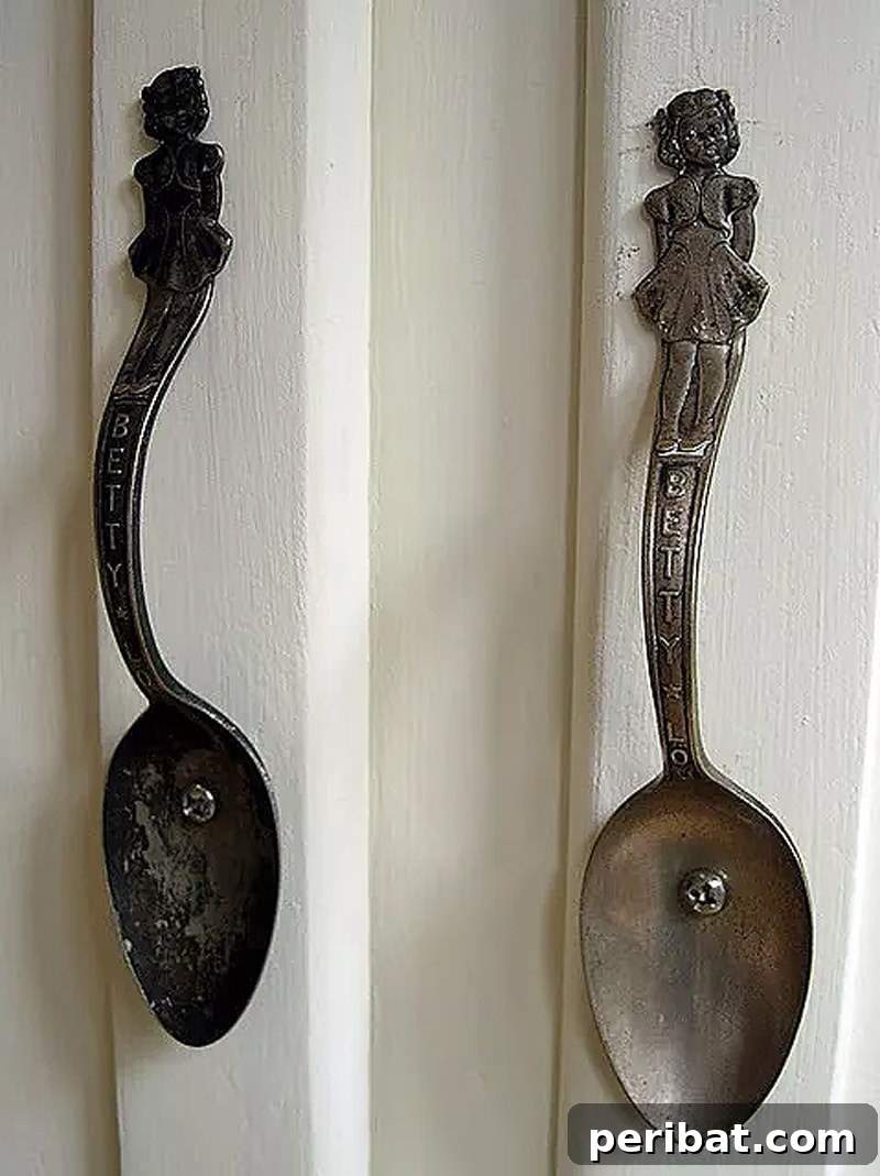 Two dark gray spoon door knobs on a wooden cabinet, demonstrating creative repurposing.