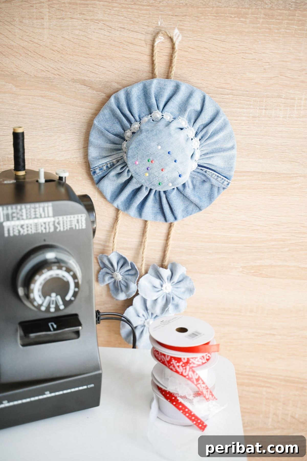 denim pin cushion hanging on wall by sewing machine table