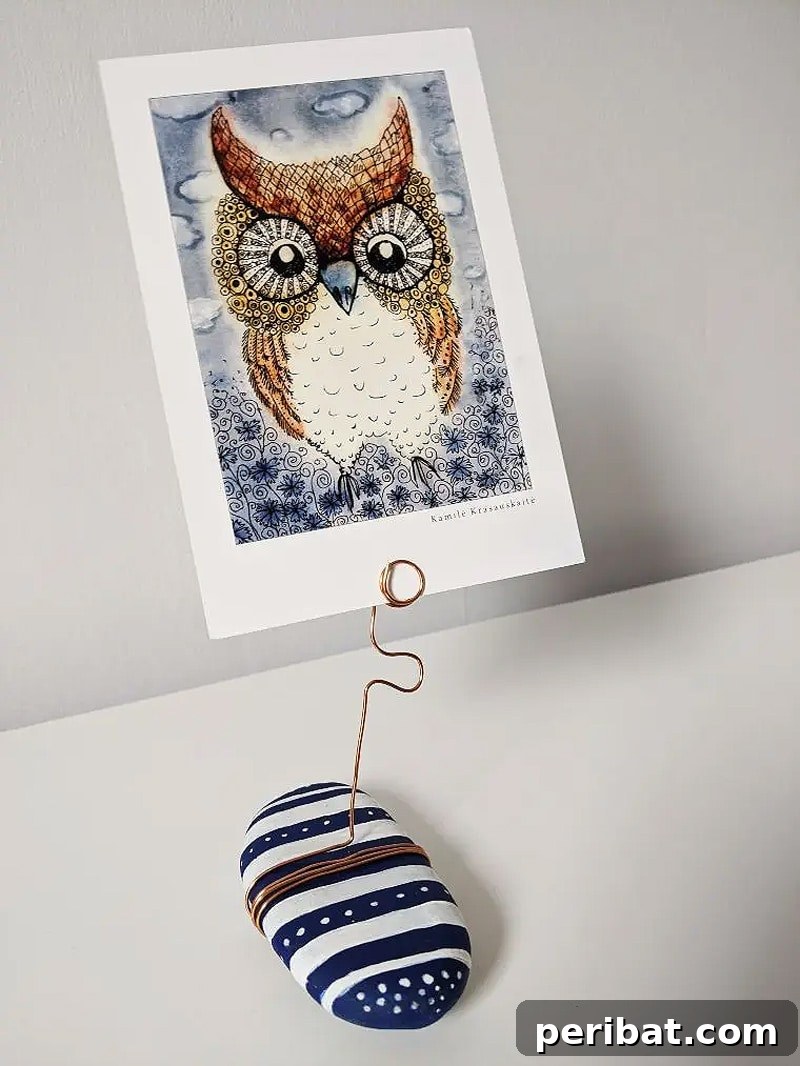 Creative Painted Rocks: Ideas, Projects, and Starter Kits 6 An owl-painted rock holding a photo with copper wire