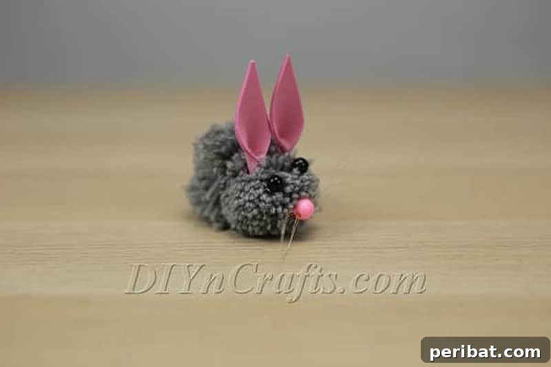 A cute, fluffy white pom pom bunny with pink ears and a tiny tail, perfect for Easter decor.