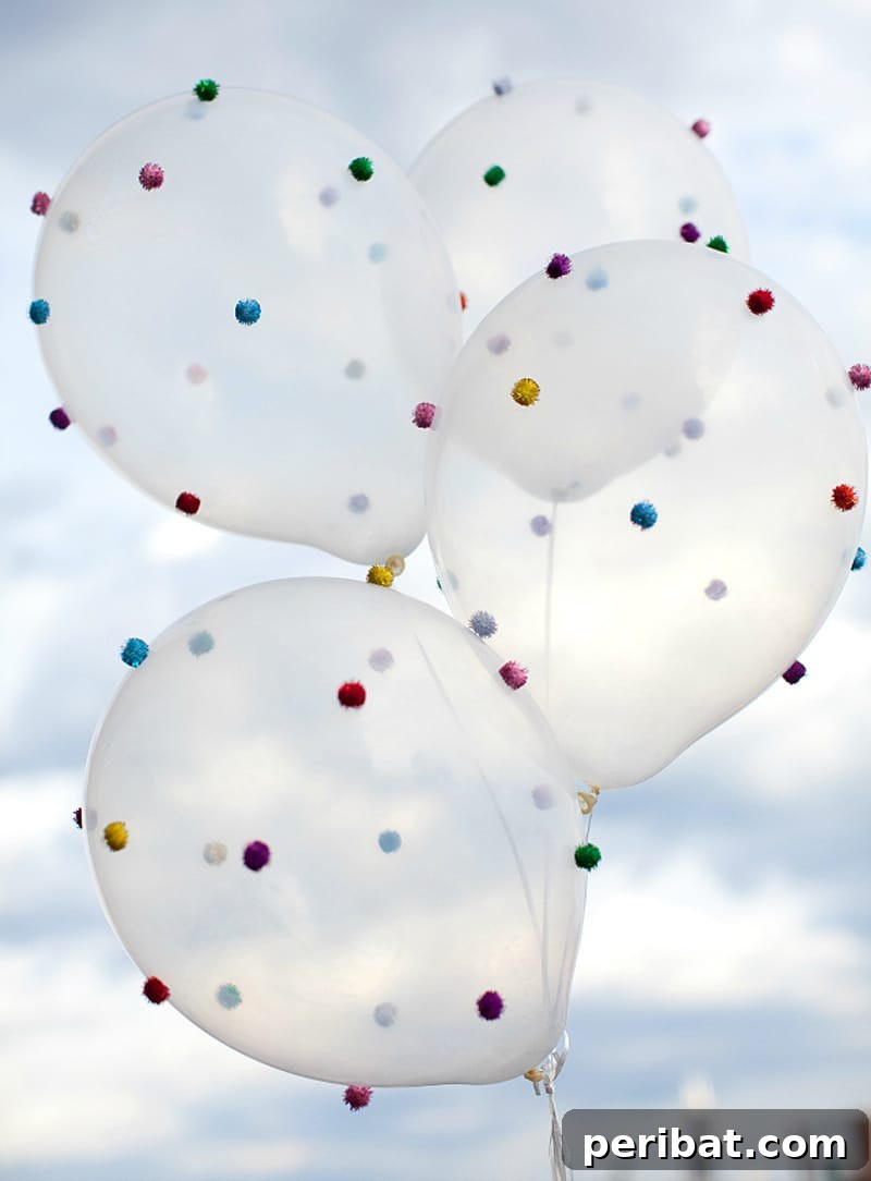 Clear latex balloons creatively decorated with small, colorful pom poms adhered to their surface, ready for a party.
