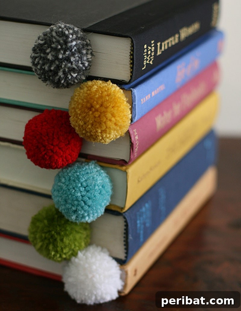 A book held open by a charming yarn ball pom pom bookmark in a light, inviting color.