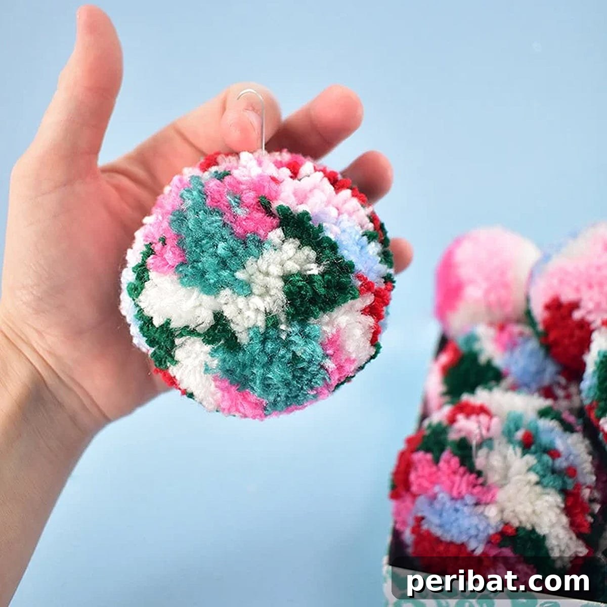 A festive Christmas tree adorned with homemade vibrant, multicolored pom pom ornaments.