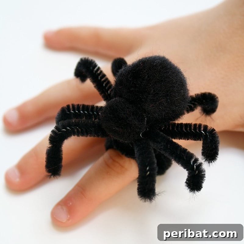 A playful DIY spider ring featuring a black pom pom body and pipe cleaner legs on a finger.