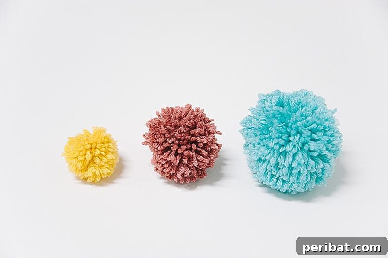 Demonstration of how to make yarn pom poms by hand, without special tools, revealing fluffy results.