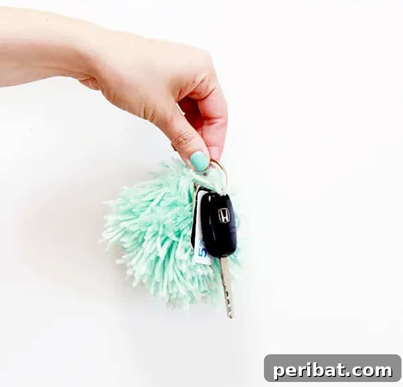 A collection of the cutest DIY pom pom keychains in various bright colors, hanging together.