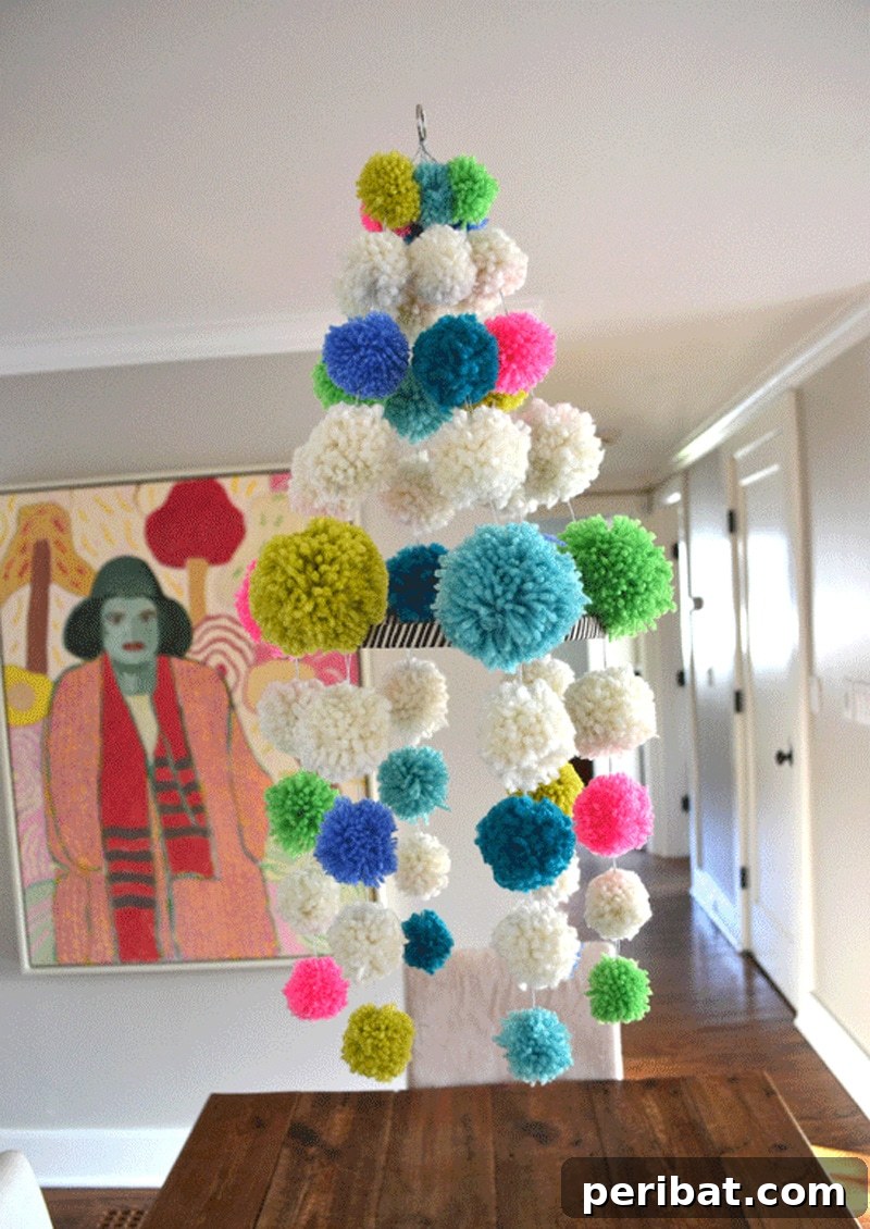 A whimsical DIY pom pom chandelier, featuring colorful neon yarn pom poms suspended from a hoop.