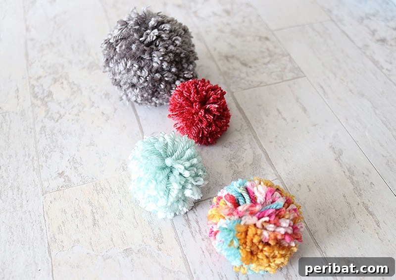 Four perfectly formed, durable yarn pom poms in different colors, demonstrating a technique for lasting quality.