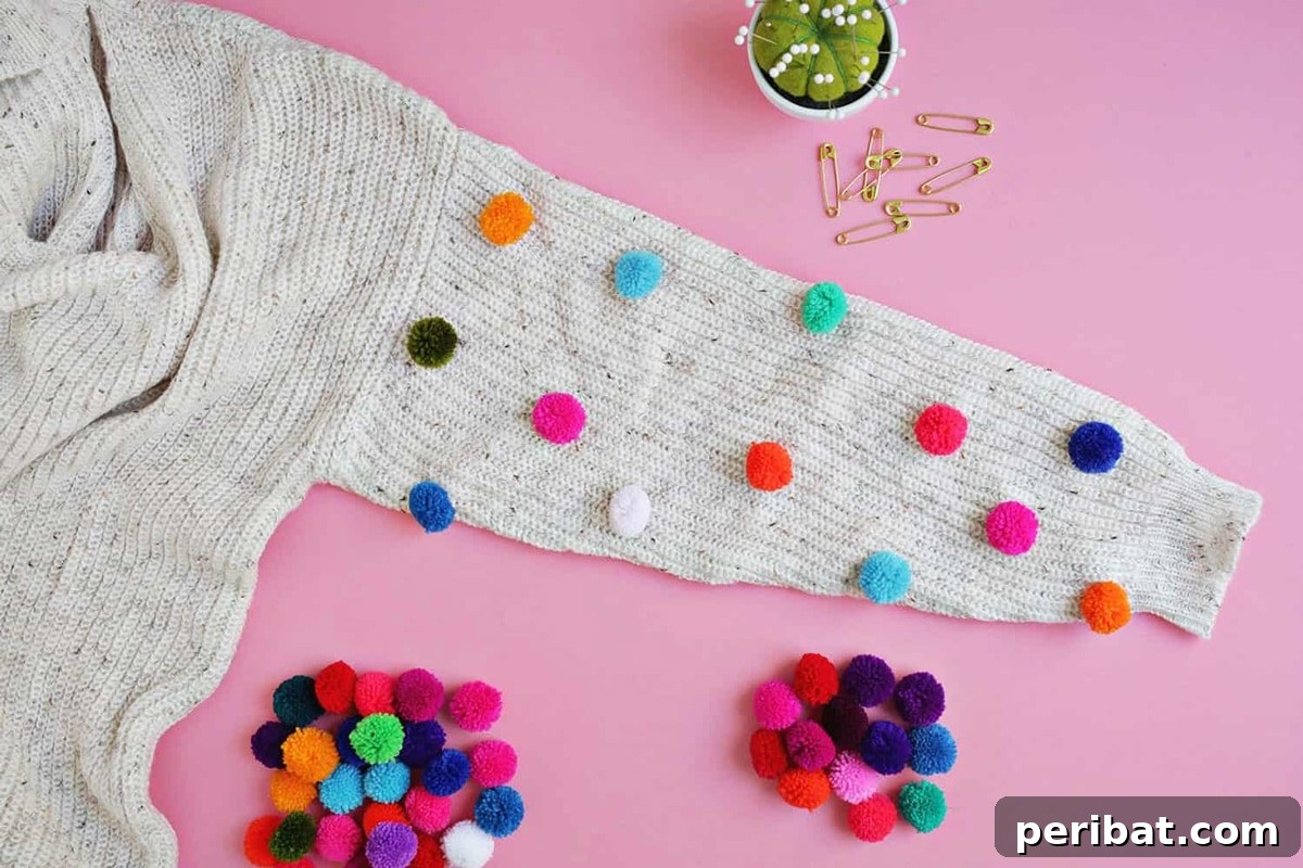 A cozy, light-colored sweater creatively enhanced with small, colorful pom poms along the sleeves.