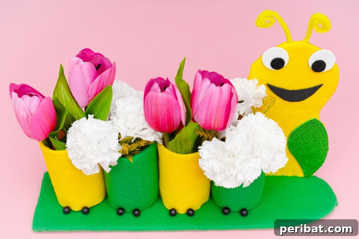 caterpillar pencil holder holding white and pink flowers on pink background